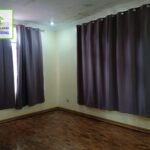 Empty room with wood floors and gray curtains.