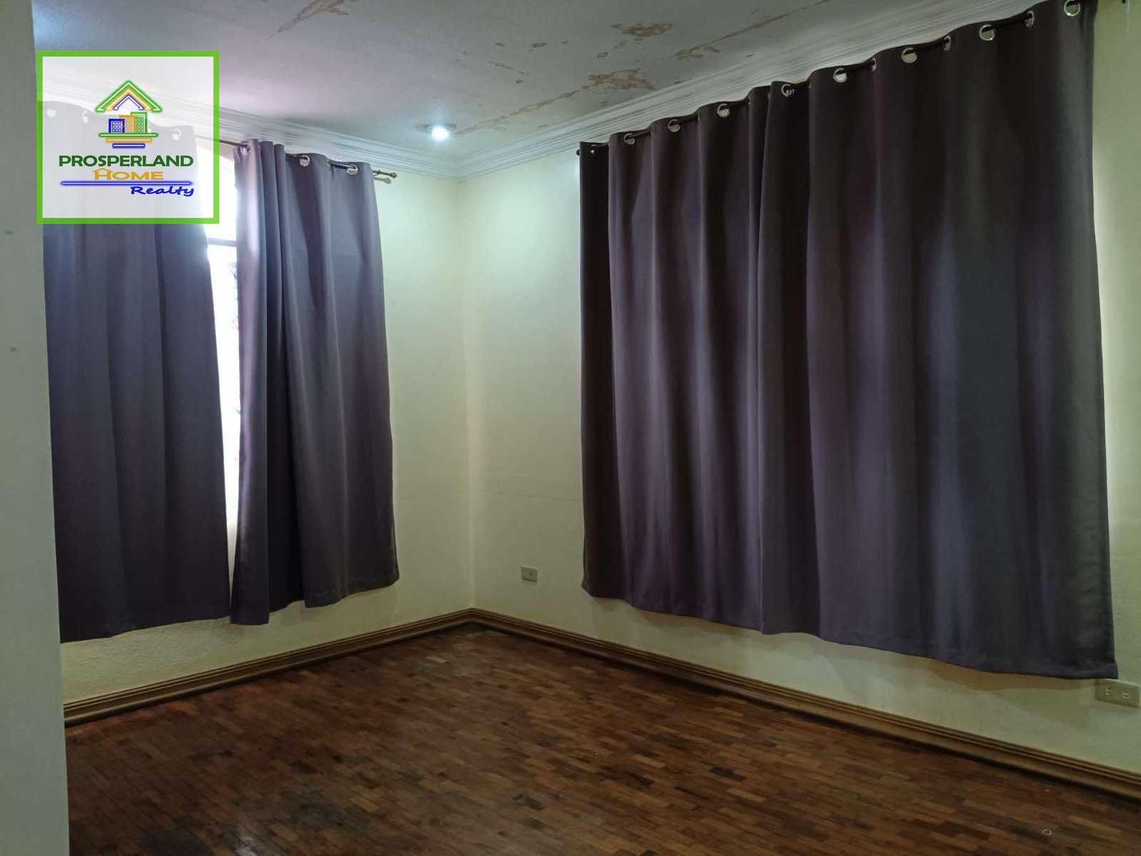 Empty room with wood floors and gray curtains.