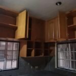 A kitchen with wooden cabinets and a window, with a real estate logo in the corner.
