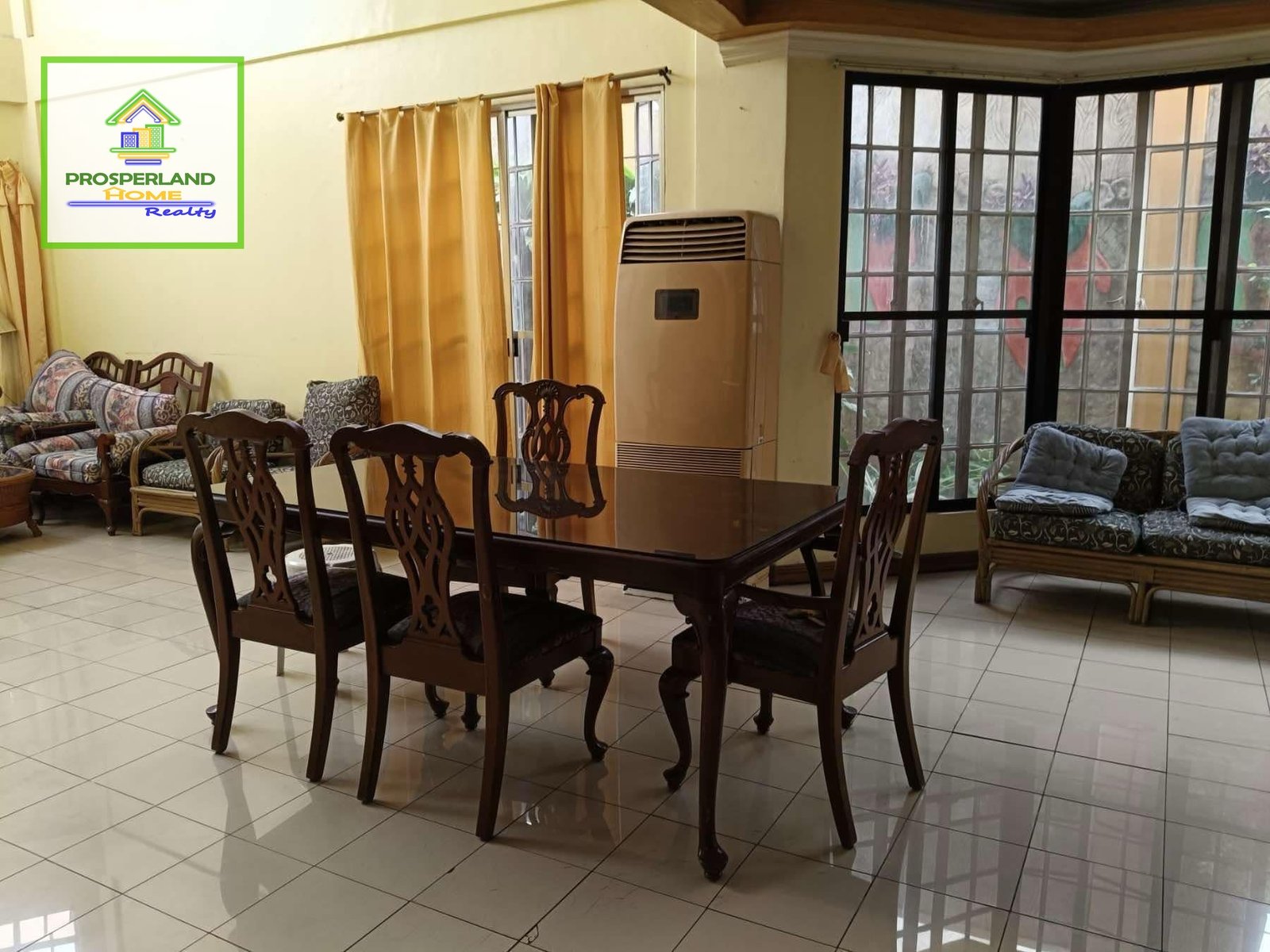 Dining room with dark wood table and chairs, tiled floor, and a seating area with decorative cushions.