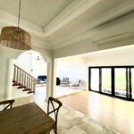 Interior of a house with a wooden dining table, stairway, and living room.