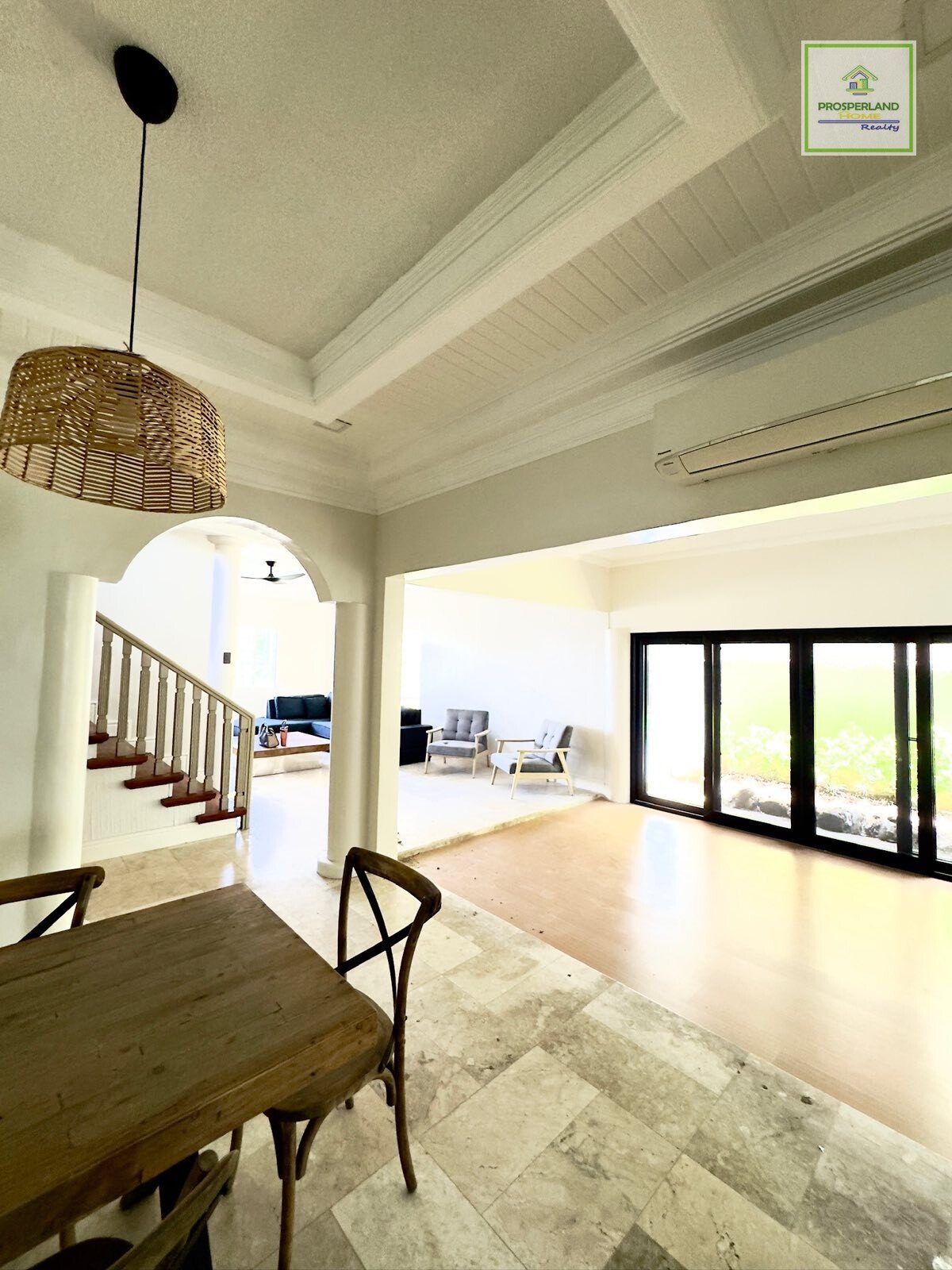 Interior of a house with a wooden dining table, stairway, and living room.