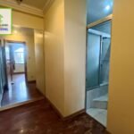 Interior shot of a hallway with a mirror reflecting another room and a bathroom entrance.
