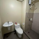 A small bathroom with a toilet, sink, and shower.