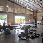 Inside a warehouse, people sort packages near vans and open loading docks.
