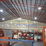 Interior view of a warehouse with crates and workers, marked with signs.