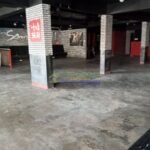 Empty commercial space with brick columns and black ceiling.