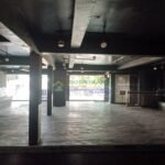 An empty commercial space with a dark ceiling and concrete floor.