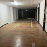 Interior view of a long, empty commercial space with tiled floors.