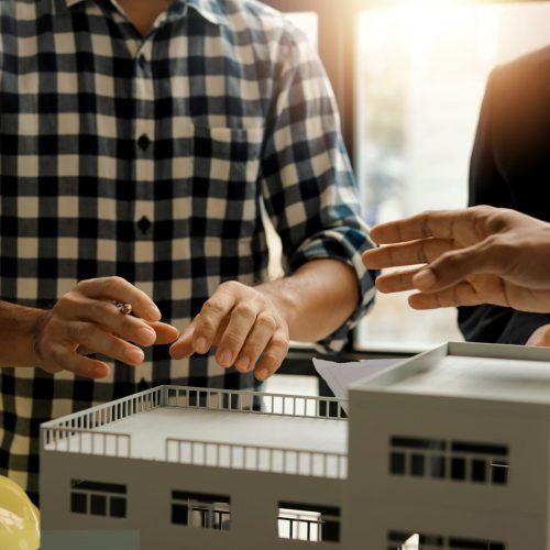 Architects and engineers discuss a building model during a meeting.