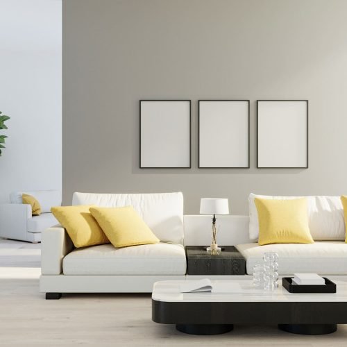 Bright living room with a white sofa, yellow pillows, and three framed posters.
